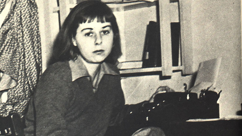 Carson McCullers sitting at a desk with a typewriter